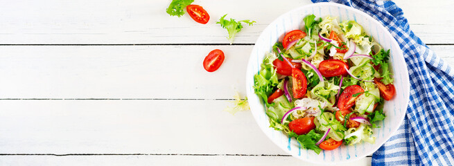 Fresh tomatoes with cucumber, lettuce, red onion and spices in a white bowl.  Concept healthy appetizer. White wooden background. Top view, overhead, copy space