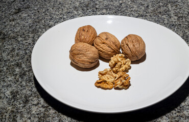 Walnuts in shell on a white plate and dark background