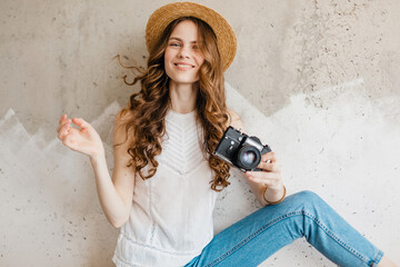 young pretty smiling happy woman in straw hat holding vintage photo camera, long curly hair