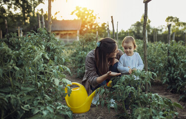 Mother and her daughter working on the organic garden. Young mother and her little daughter working on the family farm.