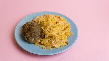 Stewed white cabbage with a cutlet steak on a plate. A dish of Russian, Polish cuisine. Garnish in the USSR.