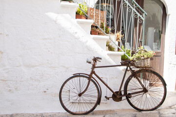Fototapeta na wymiar vintage bike resting against the wall in the white town of Ostuni in Apulia. Italian Lifestyle