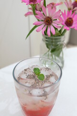 A glass of aloe vera ice drink with syrup on the table.