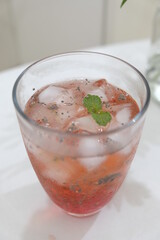A glass of aloe vera ice drink with syrup on the table.