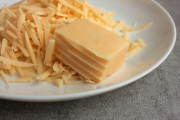 Grated cheese and a piece of cheese on a plate. Overhead view. Close-up