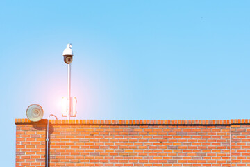 Electronic CCTV system and wall-mounted spotlights for security spy on sky blue background.