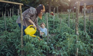 Mother and her daughter working on the organic garden. Young mother and her little daughter working on the family farm.
