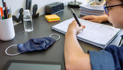 Teenager doing homework at the desk in his room