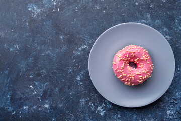 Pink donut on a plate. Top view, text space