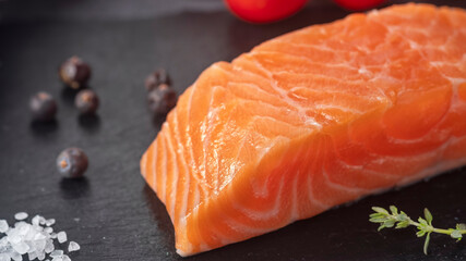 Raw salmon fillet on a black stone with spices