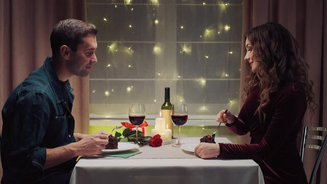 In love with a man and a woman eat together in a sweet dessert. Valentine's Day. A romantic dinner by candlelight.