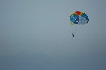 Recreational activity known as parascending or parasailing enjoyed by tourists visiting the island; adrenaline seekers strapped by a parachute enjoying being airborne, Tenerife, Canary Islands, Spain