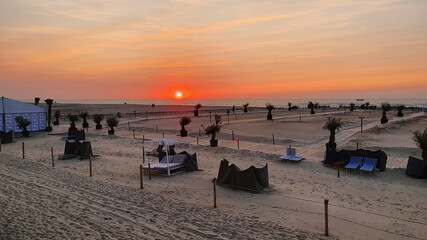 Beach wit sand and hotel, palm, cafe in the evening.