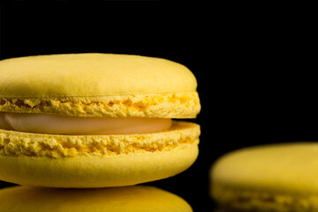 Fototapeta na wymiar French cookies. Yellow macaroons isolated on a dark, black background. almond cookies.