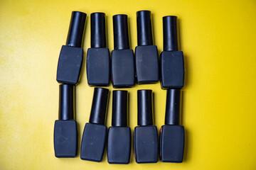 Black containers for nail polish on a yellow isolated background