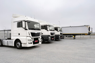 Naklejka premium Parked trucks and trailers in a parking lot. New car park, Freight transport by road, Logistics and transport