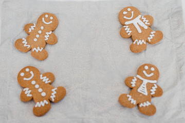 Smiling gingerbread man with sugar, spices, and vintage rolling pin on rustic, textile linen...