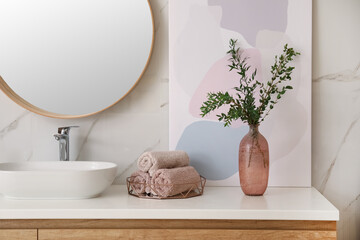 Vase with beautiful branches and fresh towels near vessel sink in bathroom. Interior design
