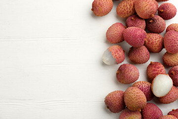 Fresh ripe lychees on white wooden table, flat lay. Space for text