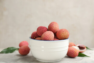 Fresh ripe lychee fruits in bowl on light grey table