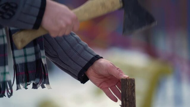 Close view man's hands try chop log. Man's hands working with ax. 
Try and do it. Man working at outdoors in cold time. 