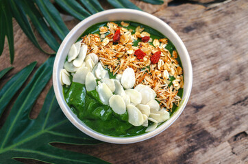 Top view Breakfast Detox Green Smoothie bowls  from Green tea and Spinach with fruits, nuts, seeds and homemade granola and  for healthy vegan on the table.