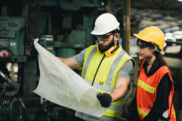 Two maintenance engineers men and women inspect relay protection system with laptop comp. They work a heavy industry manufacturing factory.