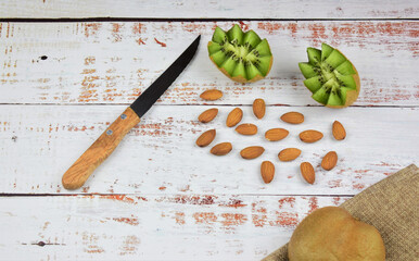 Peeled almonds and tropical fruit, kiwi, on rustic white wood. Space for texts or idea.