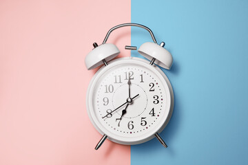 White clock alarm clock in vintage style on blue pink background