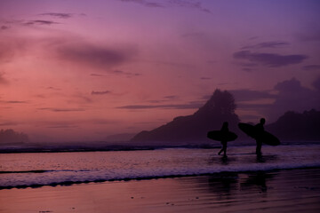 Tofino Vancouver Island Pacific rim coast, surfers with board during sunset at the beach, surfers...