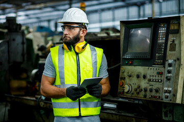 Close up hand industrial industrial plant with a tablet in hand, Engineer looking of working at industrial machinery setup in factory.