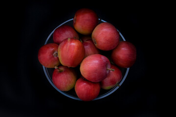 Fototapeta na wymiar Fresh red apples in bowl on dark background. Top view