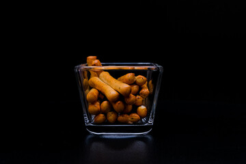 Bread sticks with poppy seeds in glass on dark background