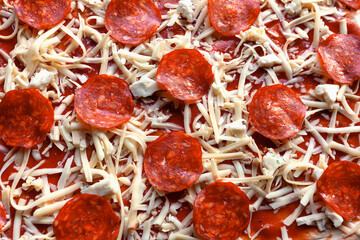 Top view of raw homemade pepperoni pizza, ready for baking