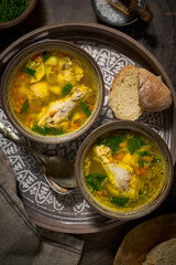 Asian style chicken soup in two clay bowls, bread, top view