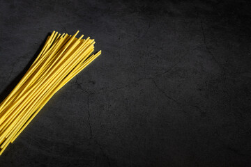 Yellow spaghetti on a black marble table. Yellow Italian Pasta. Raw spaghetti. Italian concept and menu