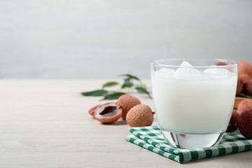Fresh lychee juice on white wooden table. Space for text