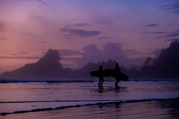 Tofino Vancouver Island Pacific rim coast, surfers with board during sunset at the beach, surfers...