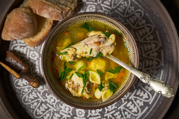 Chicken soup in a clay bowl, bread, top view