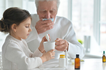 Granddaughter giving medicine to her grandfather in room