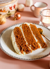Fototapeta na wymiar Piece of carrot layer cake on white plate with Christmas seasonal background