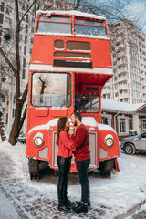 A loving couple hugs on the background of a red bus. Valentine's Day