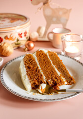 Piece of carrot layer cake, spoon on white plate with Christmas seasonal background