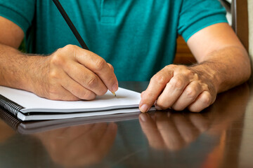 man with spiral notebook writing with pencil.