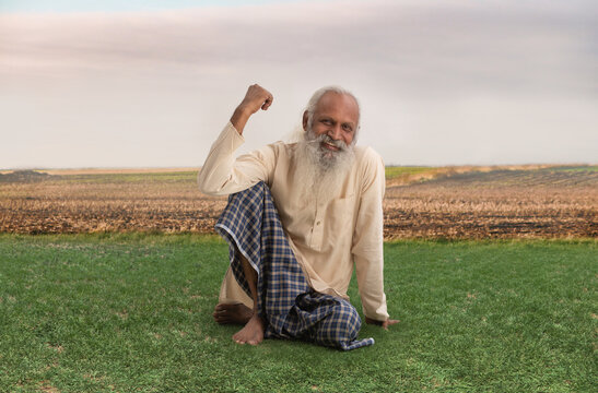 A CONFIDENT OLD FARMER SITTING AND SMILING AT CAMERA	