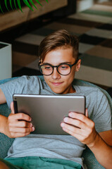 Smiling teenager boy in the glasses using tablet