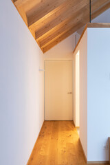 Front view hallway with white door and visible wooden beams. Nobody inside