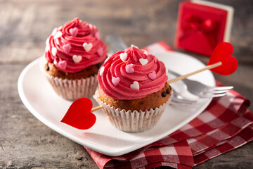 Cupcake decorated with sugar hearts and a cupid arrow for Valentine's Day on wooden table