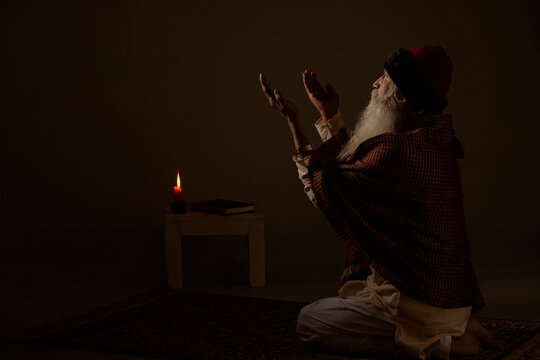 AN OLD MAN RAISING HANDS ABOVE AND PRAYING	