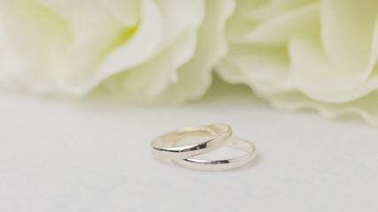 Wedding rings lie near a beautiful bouquet as bridal accessories.Wedding rings and roses bouquet.concept for a wedding card.